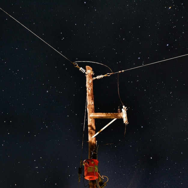 Photo vue à faible angle du pylône électrique éclairé contre le champ d'étoiles dans le ciel la nuit