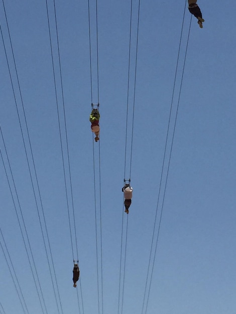 Vue à faible angle des gens en tirelire contre un ciel bleu clair