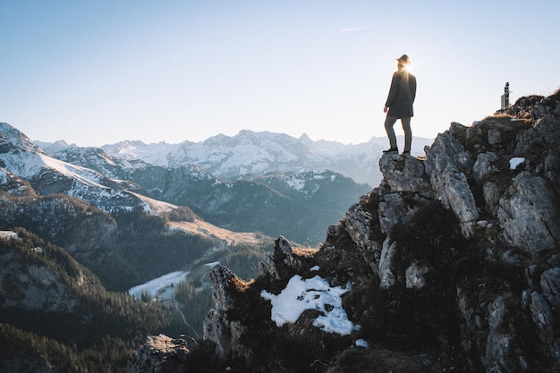 Vue à faible angle de l'homme debout sur des montagnes rocheuses contre un ciel clair pendant une journée ensoleillée
