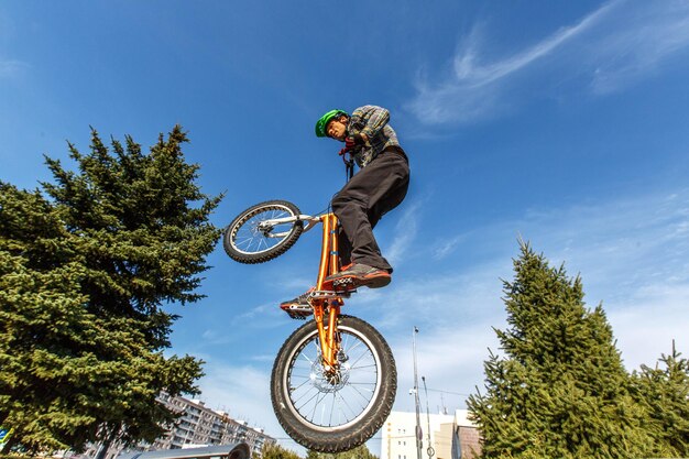 Vue à faible angle de l'homme faisant une cascade de vélo contre le ciel