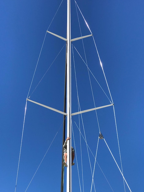 Photo vue à faible angle de l'homme grimpant sur la tour contre un ciel bleu clair