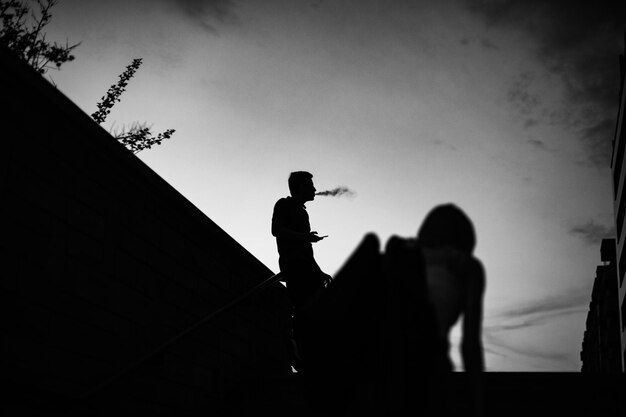 Photo vue à faible angle de l'homme silhouette fumant alors qu'il se tient contre le ciel