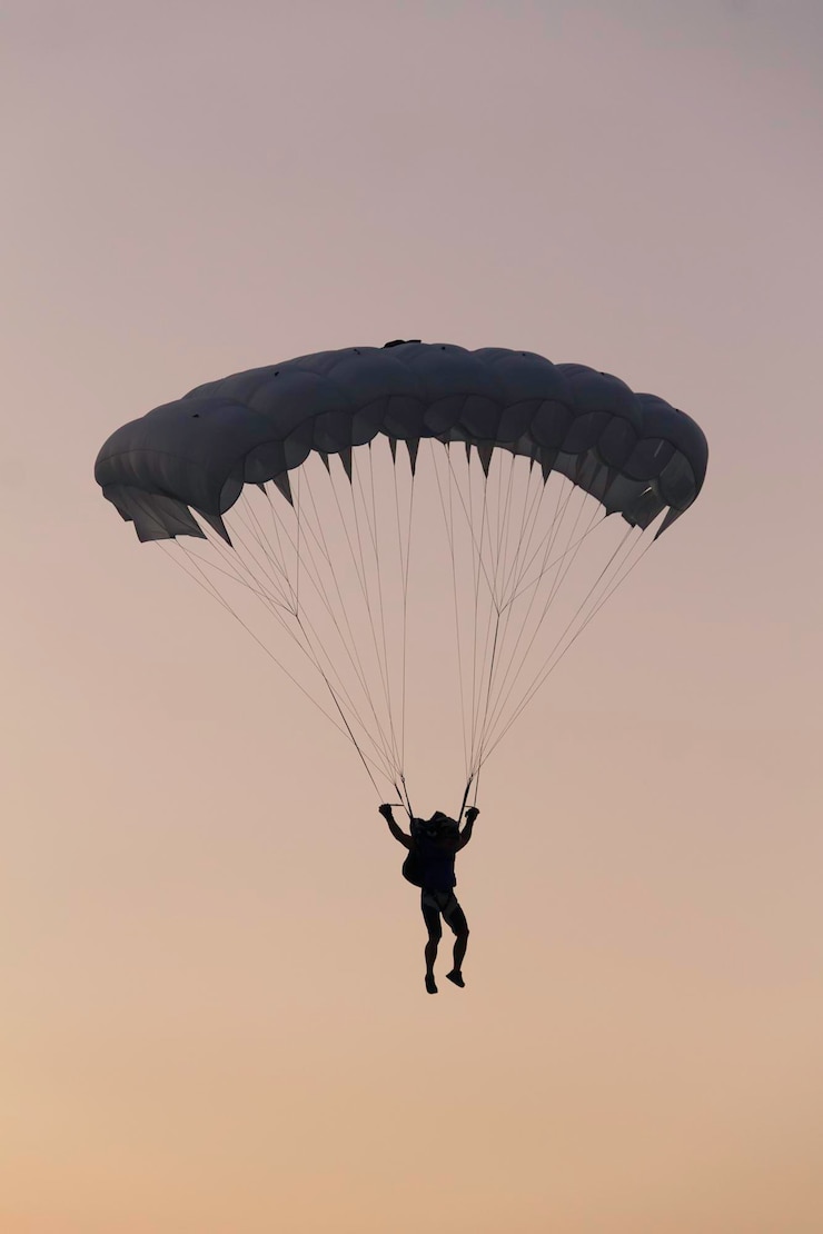 Photo vue à faible angle de l'homme en silhouette en parapente contre un ciel clair au coucher du soleil.