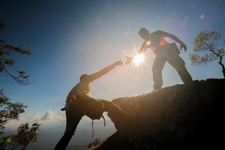 Photo vue à faible angle d'un jeune homme aidant un ami à grimper sur la roche contre le ciel pendant une journée ensoleillée