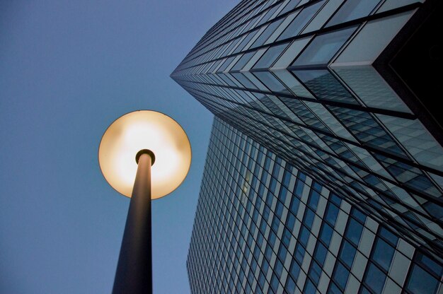 Photo vue à faible angle de la lumière de la rue éclairée par un bâtiment moderne contre un ciel clair