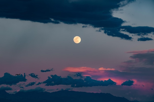 Vue à faible angle de la lune sur un ciel nuageux au coucher du soleil