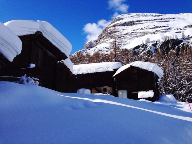 Vue à faible angle des maisons couvertes de neige contre le ciel par une journée ensoleillée