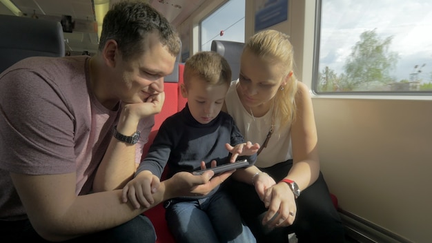 Vue de famille heureuse dans le voyage en train à l'aide d'un smartphone