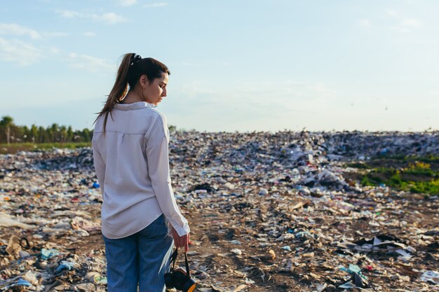 Vue d'une femme de l'arrière sur le fond de la décharge tenant un respirateur