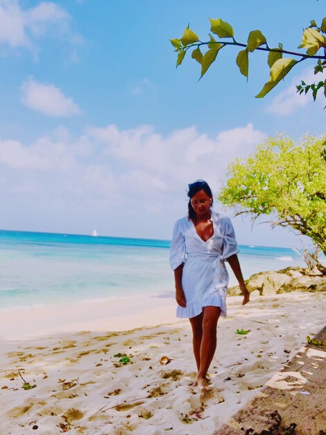 vue d'une femme debout sur la plage contre le ciel