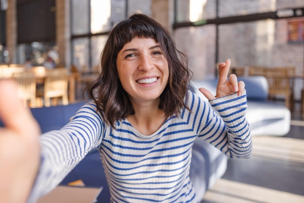 Photo vue d'une femme souriante avec des doigts croisés faisant selfie