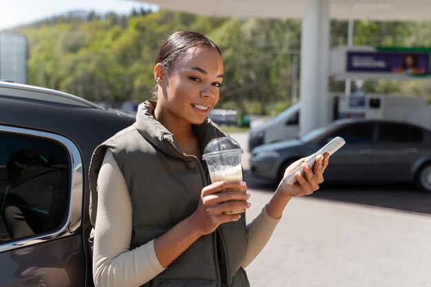 Photo vue de femme avec voiture à la station-service