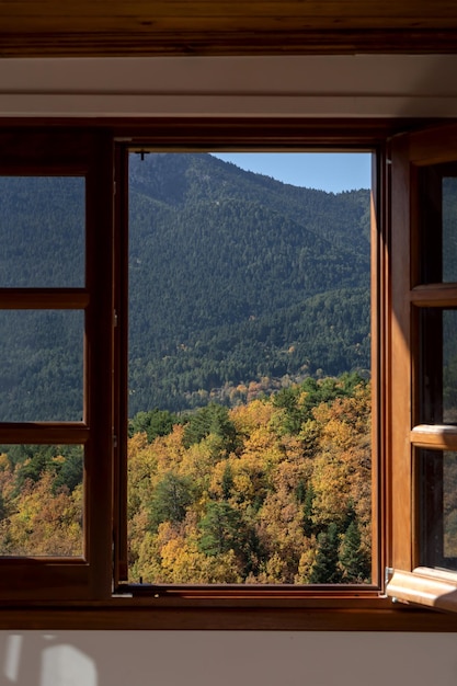 Vue d'une fenêtre ouverte sur les montagnes et la forêt par une journée d'automne ensoleillée