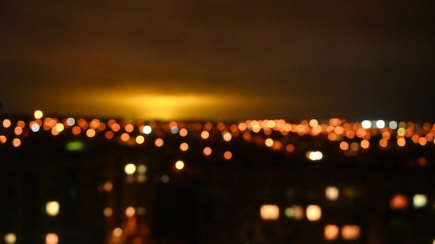 Vue floue des lumières nocturnes de la ville qui illuminent le ciel