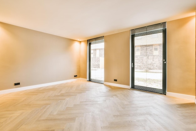 Vue générale d'une salle lumineuse vide avec de grandes fenêtres et un parquet d'une maison moderne