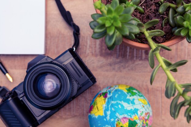 Vue grand angle de la caméra et du globe terrestre en pot sur le bureau