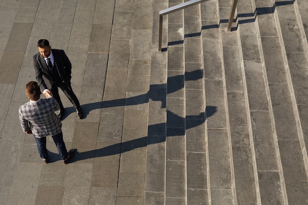 Vue grand angle de deux hommes d'affaires se serrant la main se saluant lors d'une réunion dans la ville