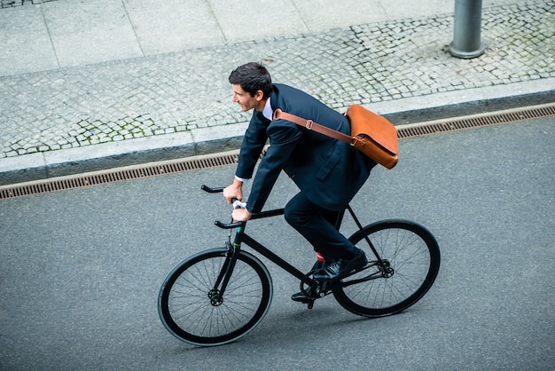 Photo vue grand angle du jeune homme portant un costume tout en conduisant un vélo utilitaire dans la rue