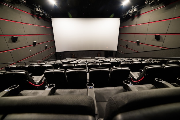 Vue grand angle de l'écran et des rangées de chaises rouges confortables dans le cinéma de la salle rouge