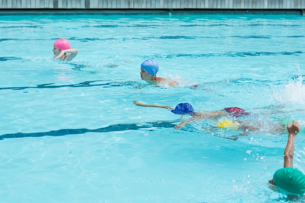 Vue grand angle des enfants nageant dans la piscine