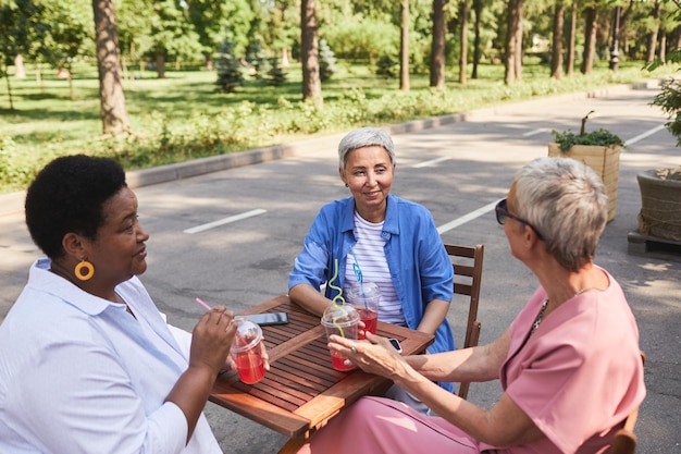 Vue grand angle sur les femmes âgées qui savourent des boissons au café en plein air