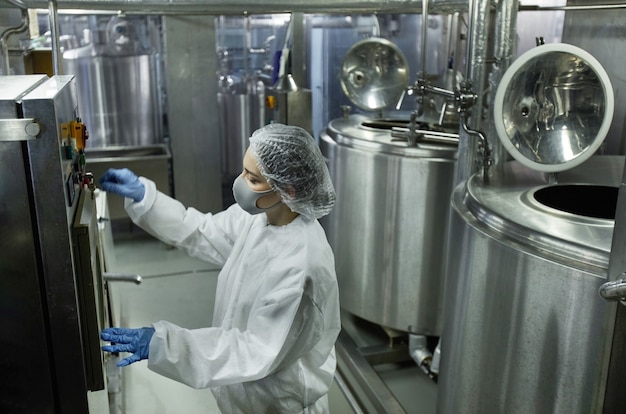 Vue en grand angle sur une jeune travailleuse opérant des unités de machine tout en travaillant dans une usine d'aliments propres, espace de copie