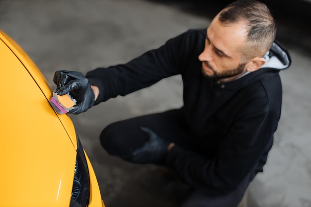 Vue Grand Angle D'un Ouvrier Professionnel Du Service Automobile Masculin Polissant Et Détaillant Une Carrosserie De Voiture