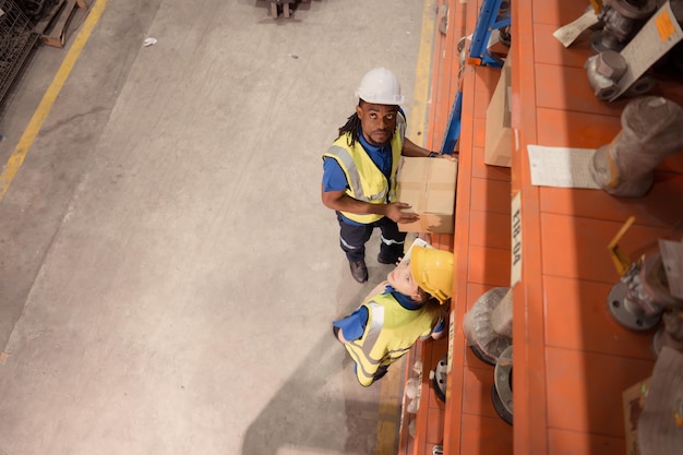 Vue grand angle des ouvriers de l'entrepôt dans les boîtes de levage des casques à l'entrepôt