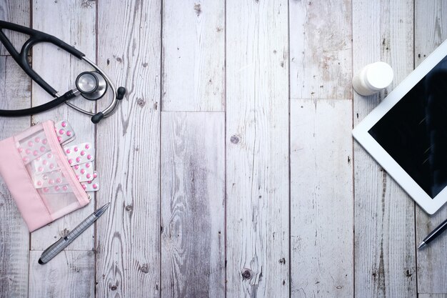 Vue grand angle de pilules, tablette numérique et stéthoscope sur le bureau de la clinique à plat