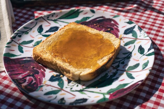 Vue hachée d'une assiette avec un toast tartiné de confiture de pêches.