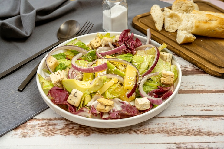 Photo vue hachée d'un bol avec salade d'un mélange de laitue, oignon rouge, avocat, fromage manchego et croûtons aux graines et à l'huile d'olive. vue horizontale