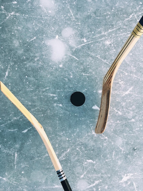 Photo vue à haut angle des bâtons de hockey sur glace et de la rondelle sur la patinoire