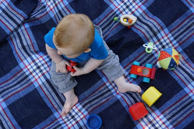 Photo vue à haut angle d'un bébé jouant avec des jouets sur une couverture