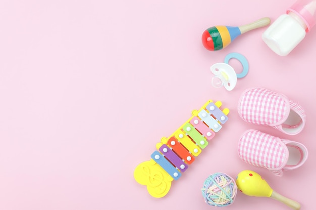 Vue à haut angle des bottes de bébé par des jouets sur un fond rose