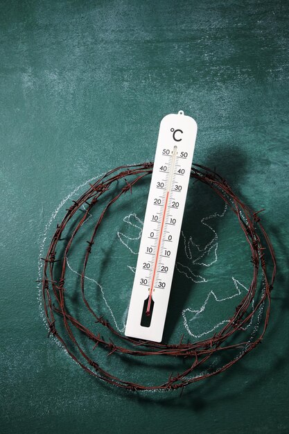 Photo vue à haut angle du fil de fer barbelé rouillé avec dessin de globe et thermomètre sur tableau noir