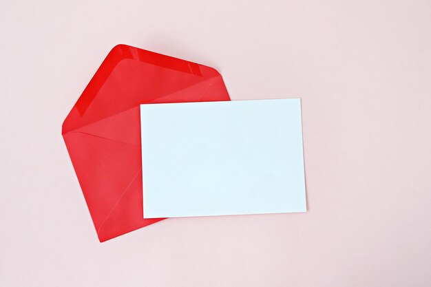 Vue à haut angle du papier blanc et de l'enveloppe sur la table contre un fond rose