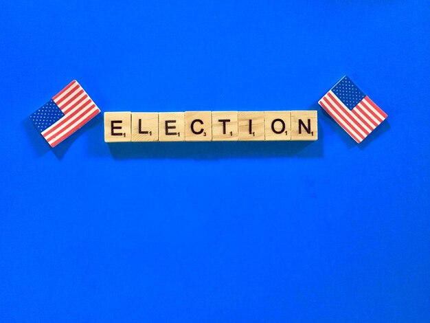 Photo vue à haut angle du texte électoral avec des drapeaux américains sur fond bleu