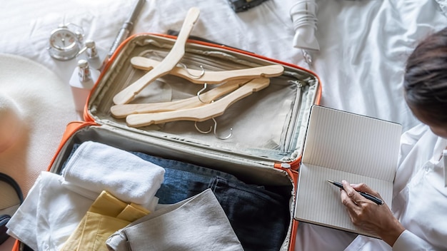 Photo vue à haut angle d'une femme emballant une valise sur le lit