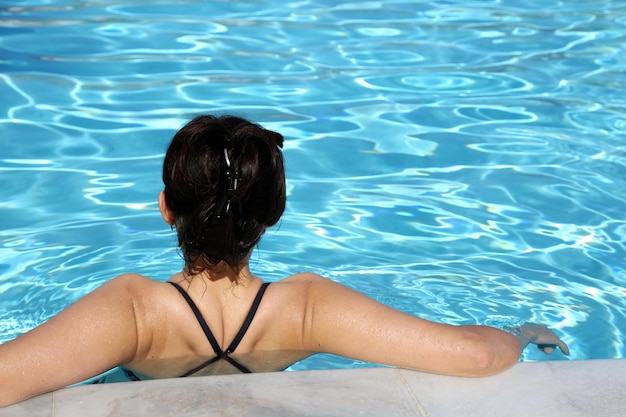 Vue à haut angle d'une femme se détendant dans une piscine un jour ensoleillé