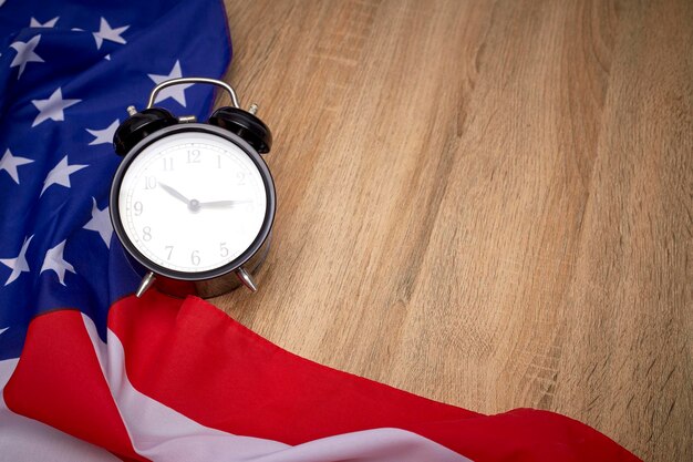 Vue à haut angle de l'horloge réveil avec drapeau américain sur table en bois