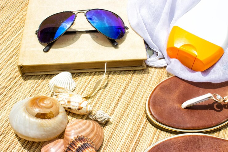 Photo vue à haut angle des lunettes de soleil avec un livre et des accessoires personnels sur le tapis