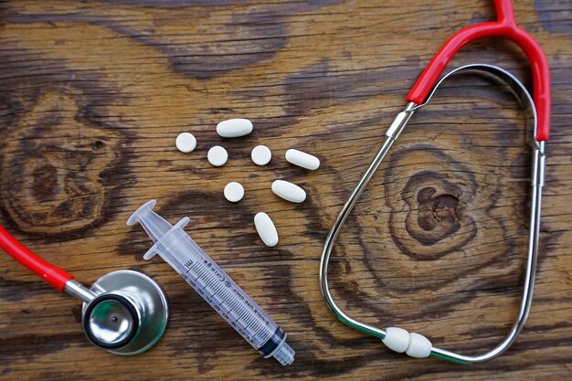 Photo vue à haut angle des médicaments avec une seringue et un stéthoscope sur une table en bois