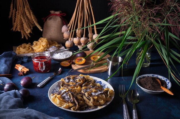 Photo vue à haut angle des nouilles de dessert de pâtes sucrées avec des graines de pavot sur une table à fond sombre