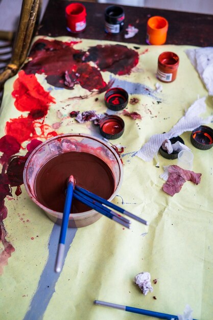 Photo vue à haut angle des palettes d'artistes éclaboussées de peinture sur la table éclairée par la lumière du soleil