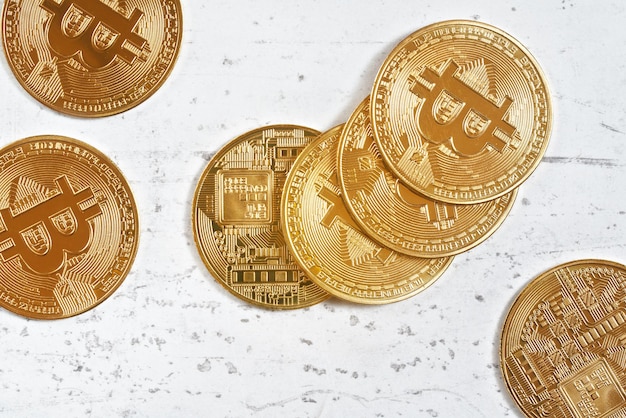 Vue de haut en bas, btc commémoratif doré - crypto-monnaie bitcoin - pièces éparpillées sur une planche en pierre blanche, gros plan détail