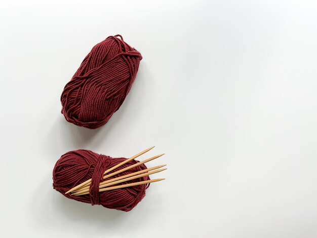 Vue d'en haut de deux toiles rouges en laine avec des aiguilles en bois pour le tricot