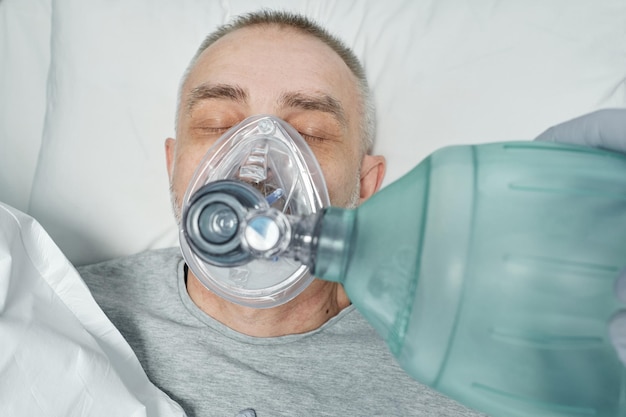 Photo vue d'en haut d'employés médicaux méconnaissables effectuant la rcp pour un patient adulte dans la salle d'urgence