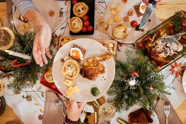 Vue de haut en gros plan des mains qui taillent une dinde rôtie pendant un dîner de famille de Noël à la table