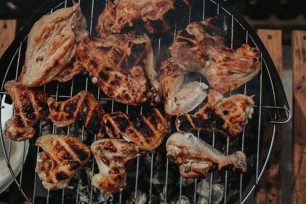 Vue d'en haut de la poitrine de poulet surcuite et des ailes sur un gril à l'extérieur