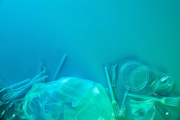 Photo vue d'en haut de sacs en plastique froissés, de tasses et d'ordures en carton avec espace de copie en lumière bleue